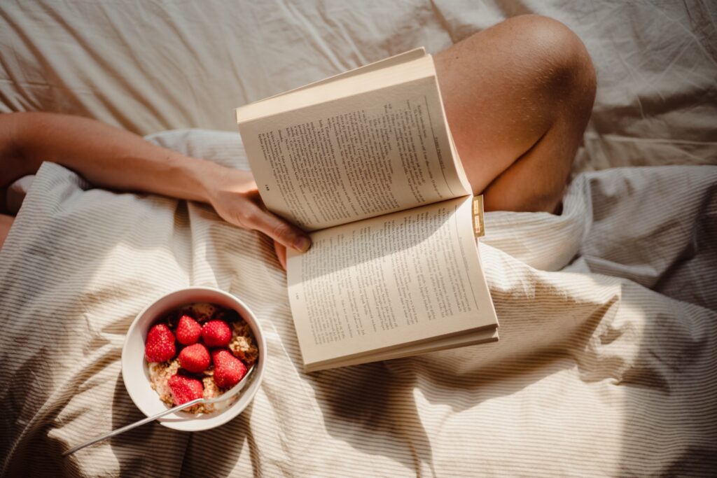 person reading book on white textile